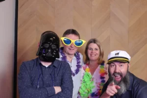 4 personen met maskers poseren voor photobooth op bedrijfsfeest